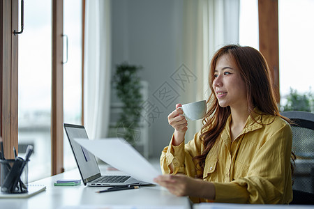 一个快乐的亚洲女人的肖像 白天咖啡休息时在她桌上微笑互联网技术人士商务水平咖啡杯成人倾斜腰部中年人图片