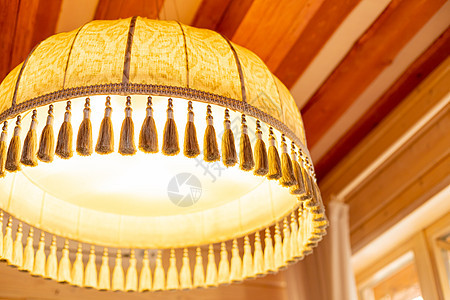 带边缘的大型黄色织物灯罩作为复古装饰的元素 旧式复古灯罩 吊灯的纺织品装饰 挂在房间里的装饰灯图片