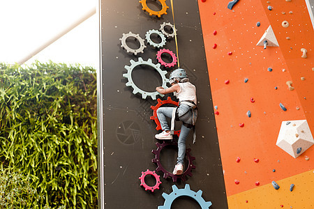 儿童在娱乐中心的墙上攀爬 儿童攀岩训练 穿着登山装备的小女孩爬得很高 为孩子们提供极度活跃的休闲活动操场齿轮安全运动服围墙绳索登图片