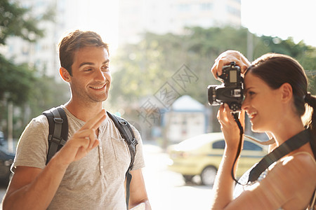 下飞机后的第一张照片 一位年轻女子在国外城市旅游时为男友拍照背景图片