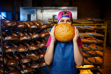 在面包店烘烤的阶段 在面包店货架的背景下 一个手里拿着面包的面包师女孩的画像 面包师的手用面包 工业面包生产微笑青年食物烤箱烹饪图片