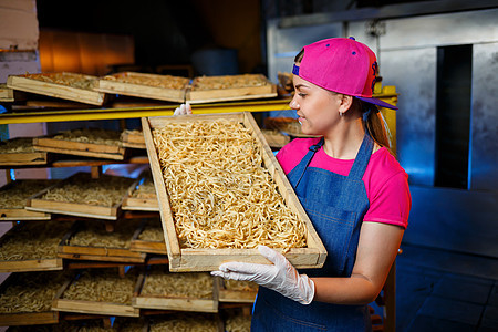 做面条 面食厂 意大利面生产 生意大利面 拿着一盒意大利面的工人 女孩在意大利面的生产中工作产品就业输送带营养制造公司机械工厂经图片