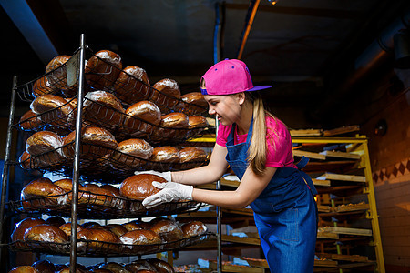 一个年轻女孩在一家面包店工作 她把面包放在架子上 面包店工作场所的女面包师 一位专业面包师手里拿着面包 面包生产理念女性食物咖啡图片