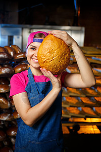 在面包店烘烤的阶段 在面包店货架的背景下 一个手里拿着面包的面包师女孩的画像 面包师的手用面包 工业面包生产粉红色围裙青年小麦女图片