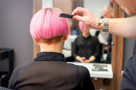 一个理发师正在梳理 美发沙龙的女客户染色粉红色短发 后视女士女性成人梳子职业理发治疗造型师行动发型图片