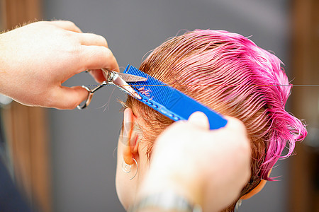 专业发型师正在剪短粉红色头发 在发廊剪剪刀合上成人理发工具造型师剪发发型职业女士女性客户图片
