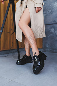 一位年轻女子穿着时髦的黑皮鞋 双腿细美 坐在制片厂的椅子上 她们很时髦的卷饼 近身装饰衣服头发艺术女性外套皮革魅力脚跟办公室横幅图片