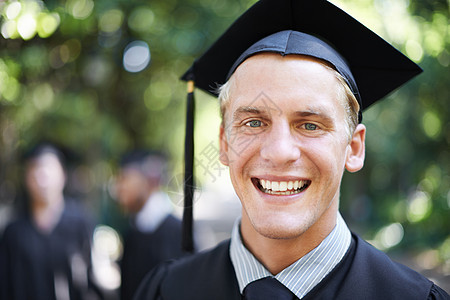 我等了一辈子才到今天 毕业日和背景中其他学生一起的一位快乐的男学生的肖像 (笑声)图片