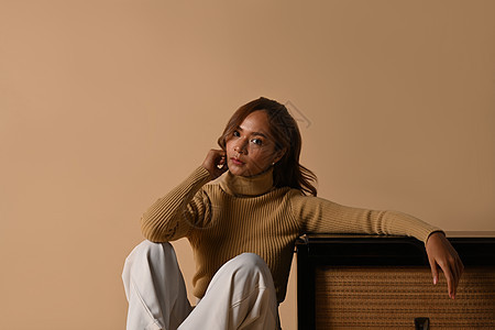 穿着时髦毛衣的时装女性肖像坐在古老电台附近 拍摄室以蜜蜂背景拍摄图片
