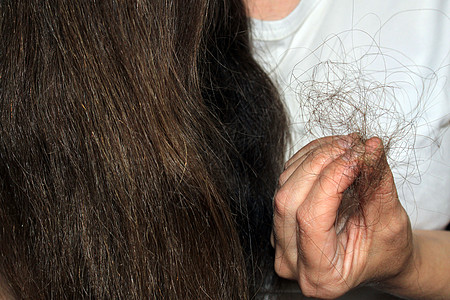 长发黑发的女孩手上握着一堆掉下来的头发 毛发有问题图片