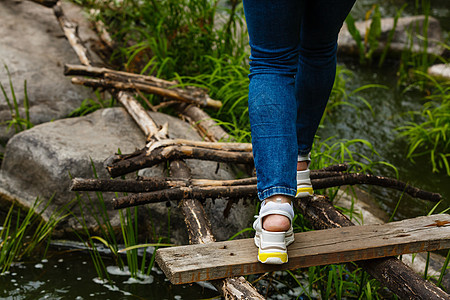 女人走在河对面的踏脚石上公园民众享受季节冒险运动娱乐岩石溪流踪迹图片