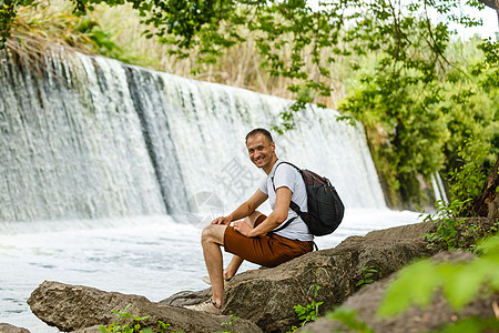 在旅游瀑布背景的肩膀上旅行的背包套件 近身登山旅行旅行迷途概念岩石游客男人自由荒野环境活动娱乐石头冒险图片