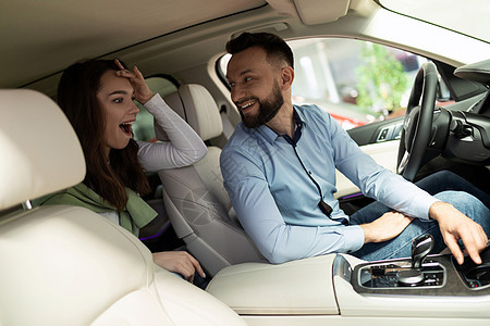 汽车经销店的一男一女坐在车里 对新技术和促销感到惊讶图片