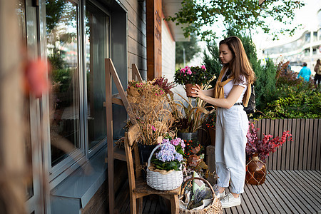 欧裔女性选择鲜花作为街头花园小摊的礼物市场购物玫瑰城市女士零售店铺快乐花园红色图片