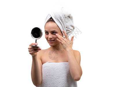 美丽的中年女性 皮肤穿衣精细的中年妇女 脸上涂着奶油 脸朝白底面照小镜子背景图片