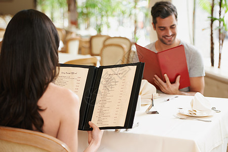 一对快乐的年轻夫妇在豪华餐厅 看着菜单看菜单 他们就喜欢吃甜食吗?图片