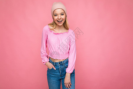 照片中 美丽 微笑 快乐的金发女郎被隔离在粉红色背景墙上 戴着时髦的粉红色帽子和粉红色衬衫 看着相机图片