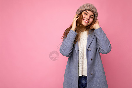 美丽 积极 快乐的黑发年轻女性 与色彩缤纷的背景墙隔绝 穿着休闲时尚的衣服 看着镜头 感觉真挚喜悦灰色帽子外套粉色毛衣灰帽服装空图片