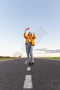 冷酷的现代少女女孩 在孤独的路上摆姿势旅游街道假期乐趣自拍自由女士游客旅行日落图片
