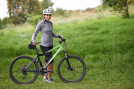 她是一位自豪的山地车手 站立在她的自行车旁边的一位可爱的女性骑自行车者图片