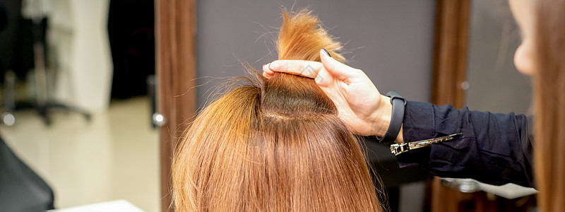 美发师在女性头发的手指间握着一根线 在美发沙龙检查年轻女子的头发造型师工作理发成人治疗顾客棕色美容师发型女士图片