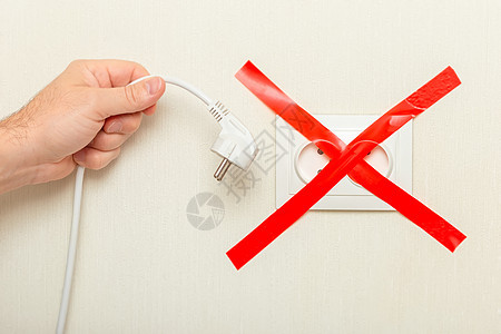一只男人手握着一条细管的白绳 插在电源出口附近 与红丝带交叉绑在一起图片