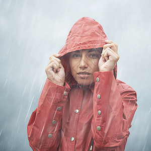 灰色天空 一个年轻女子站在雨中 拉起头罩的肖像被剪除图片