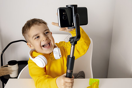 可爱 可爱 小男孩博主记录生活方式博客 与三脚架上的智能手机相机交谈 年轻有影响力的人为他的频道拍摄视频博客 孩子在网上为他的追图片