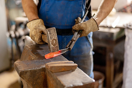 特写加热金属和铁砧的视图 铁匠在锻造中手工制作金属产品的生产过程 铁匠用锤子锻造金属 金属工业 古老的职业工匠铁工工作工艺男人作图片