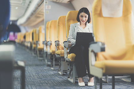 旅行前在飞机上用笔记本电脑工作的亚洲女商业妇女图片