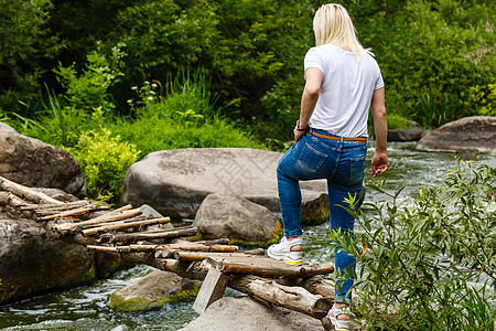 女人走在河对面的踏脚石上小路冒险路线公园旅行森林环境踪迹民众女性图片
