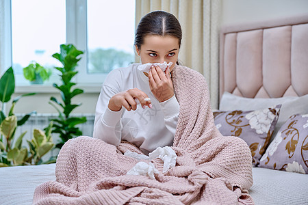 少女坐在床上 鼻子流鼻涕 拿着药品 在组织内喷喷喷雾女性诊断保健治疗女士感染过敏餐巾卫生温度图片