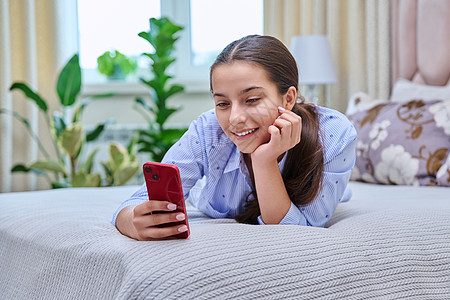 带着智能手机躺在家中的年轻少女女子电话沙发公寓互联网青少年喜悦微笑成人女士女孩图片