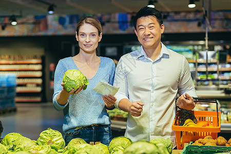 一对年轻异族夫妇 一名欧洲妇女和一名亚洲男子的画像买蔬菜图片