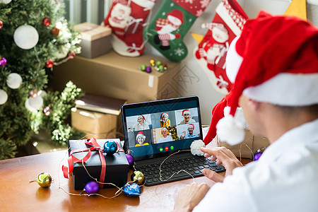 男人在家中的圣诞节 戴着圣达克休斯帽和平板电脑传统银行工具视频购物通讯眼镜笔记本假期公寓图片