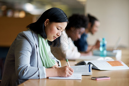 一位在图书馆学习的年轻女子和其他学生一起学习 她将获得一些最后一分钟的知识思维测试青年考试友谊校园图书幸福教育阅读图片