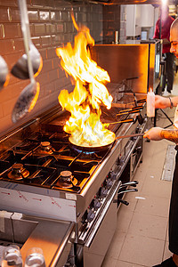 厨师在炉子上点着火准备菜盘图片