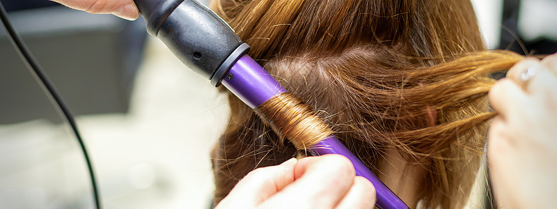 发型师在美发沙龙用卷发器做棕色长发的卷发 特写理发师职业女性洗发水造型婚礼商业客户造型师头发图片
