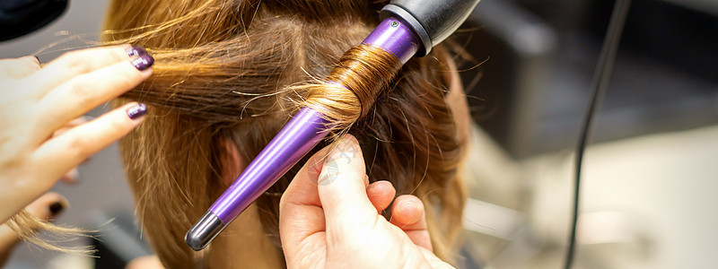 发型师在美发沙龙用卷发器做棕色长发的卷发 特写客户女性卷曲头发服务理发师造型师女孩职业理发图片
