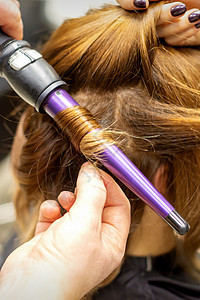 发型师在美发沙龙用卷发器做棕色长发的卷发 特写女性梳妆台头发女孩理发化妆品顾客理发师发型造型师图片