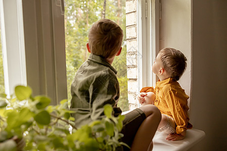 孩子们坐在窗台上等着有人来 两个兄弟 朋友 可爱的学龄前儿童独自在家 男孩们正在等待他们的母亲或父亲 孤独 忙碌的父母孩子友情男图片