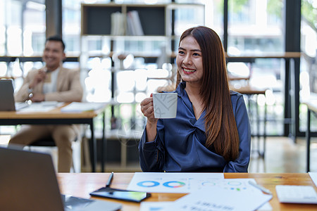 一个快乐的亚洲女人的肖像 白天咖啡休息时在她桌上微笑摄影咖啡杯中年人金发享受互联网长发生意倾斜休闲图片