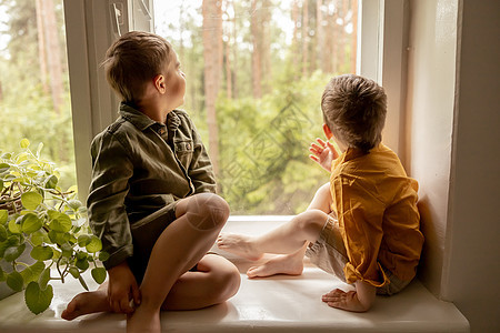 孩子们坐在窗台上等着有人来 两个兄弟 朋友 可爱的学龄前儿童独自在家 男孩们正在等待他们的母亲或父亲 孤独 忙碌的父母男性亲戚朋图片