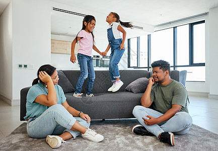 家庭 精力和孩子在家里的沙发上跳跃 疲惫的父母与顽皮 多动和玩耍的孩子作斗争 患有多动症的男女 吵闹和大笑的女孩 朋友或有趣的双图片