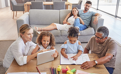 家庭 教育和祖父母帮助孩子们在绘画书和平板电脑上学习功课 老人和老妇教孩子 父母在家里的沙发上放松图片
