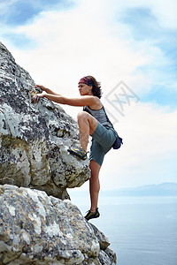 在阳光明媚的一天 有个女人在石脸上举起石头成人女性登山天空远足旅行岩石运动乐趣训练图片