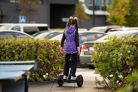 骑电动滑板车的小女孩 个人生态交通工具 陀螺滑板车 智能平衡轮 流行的电动交通工具公园学校力量童年陀螺仪摩托车喜悦街道运动木板图片