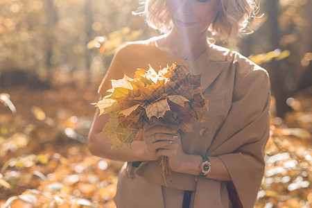 女人拿着秋叶的花束 季节和秋天的概念图片
