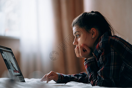 年轻妇女在床上用笔记本电脑工作卷曲说谎快乐互联网企业家女性卧室博主技术女士图片