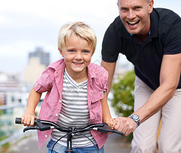 特殊的父子时刻 一个快乐的父亲教他的儿子如何骑自行车图片